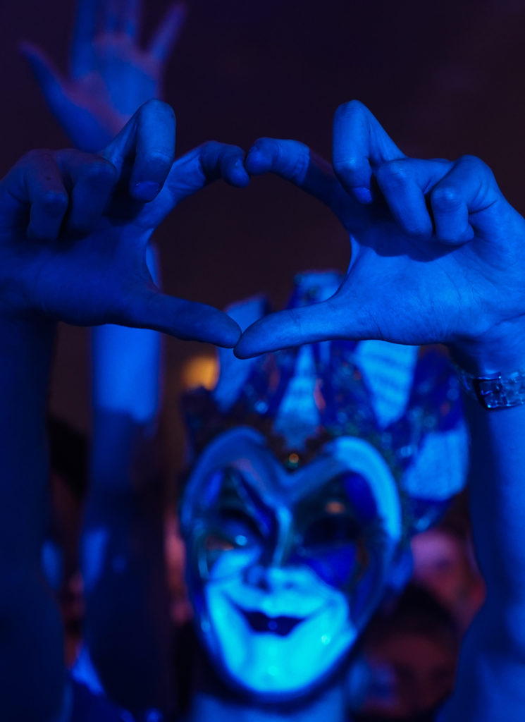 Un festivalier avec un masque fait un coeur avec les mains